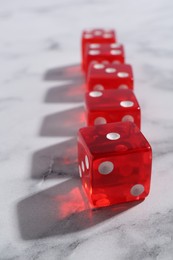 Many red game dices on white marble table