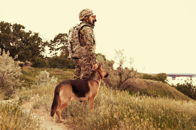 Image of Man in military uniform with German shepherd dog outdoors