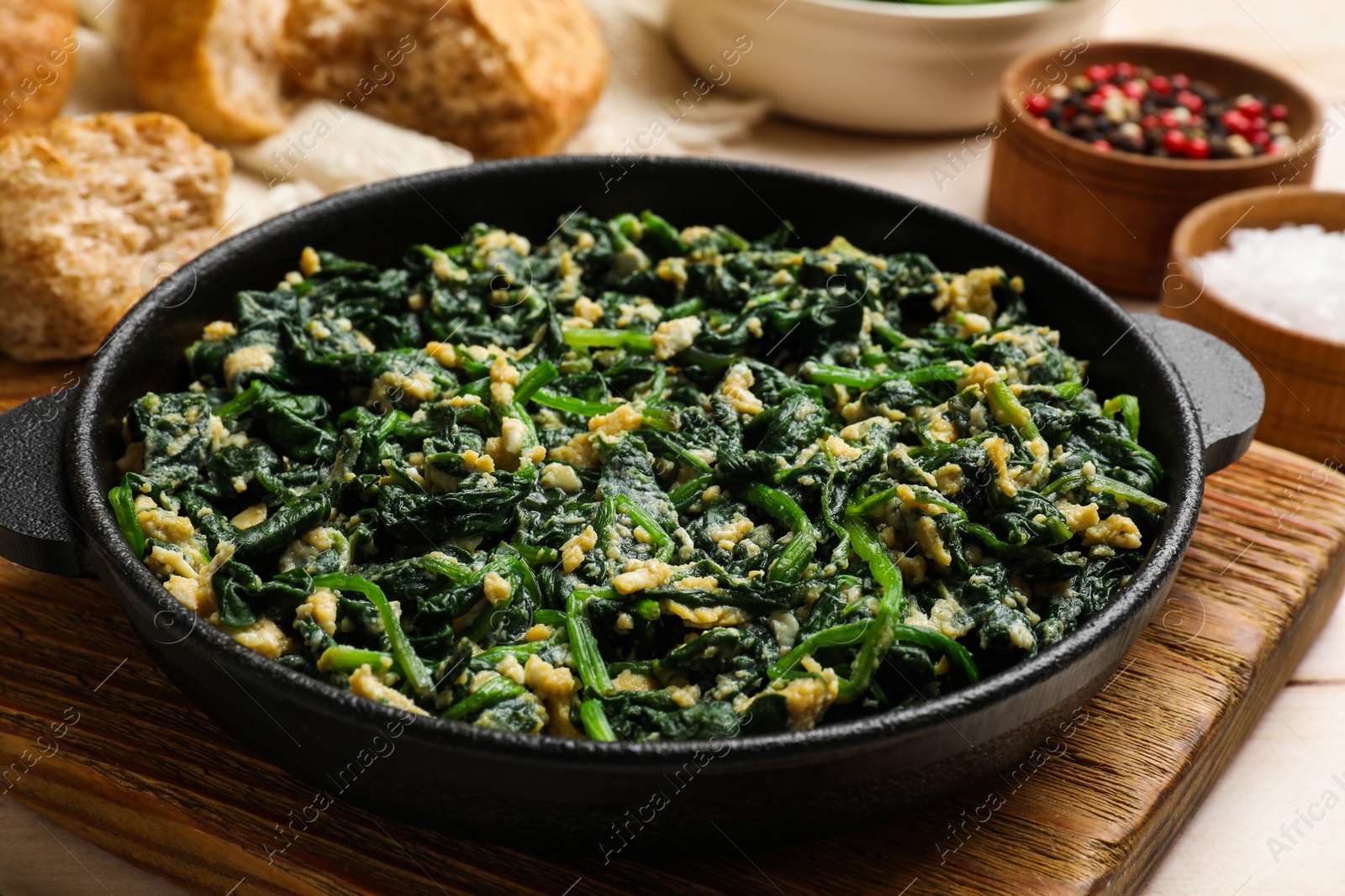 Photo of Tasty spinach dip with eggs in dish served on light wooden table, closeup