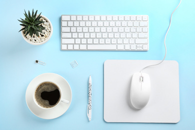 Flat lay composition with mouse and cup of coffee on light blue background