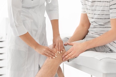 Doctor examining male patient with injured leg, closeup