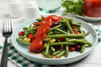 Delicious salad with green beans and tomato sauce served on white wooden table