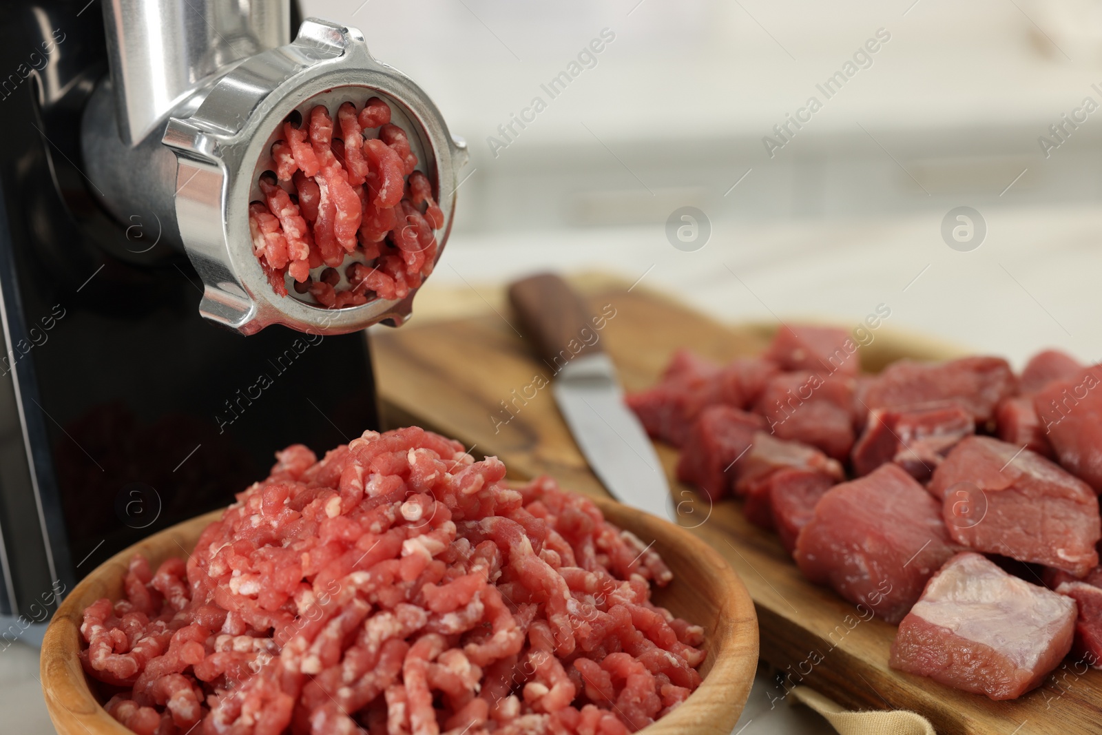 Photo of Electric meat grinder with beef on white table, closeup. Space for text