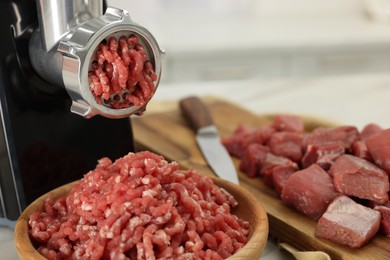 Photo of Electric meat grinder with beef on white table, closeup. Space for text