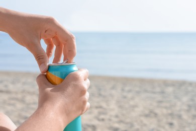 Photo of Woman opening aluminum can with beverage on beach, closeup. Space for text