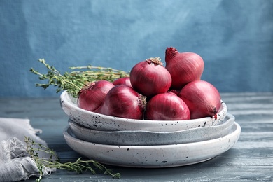 Photo of Plates with ripe red onions on wooden table