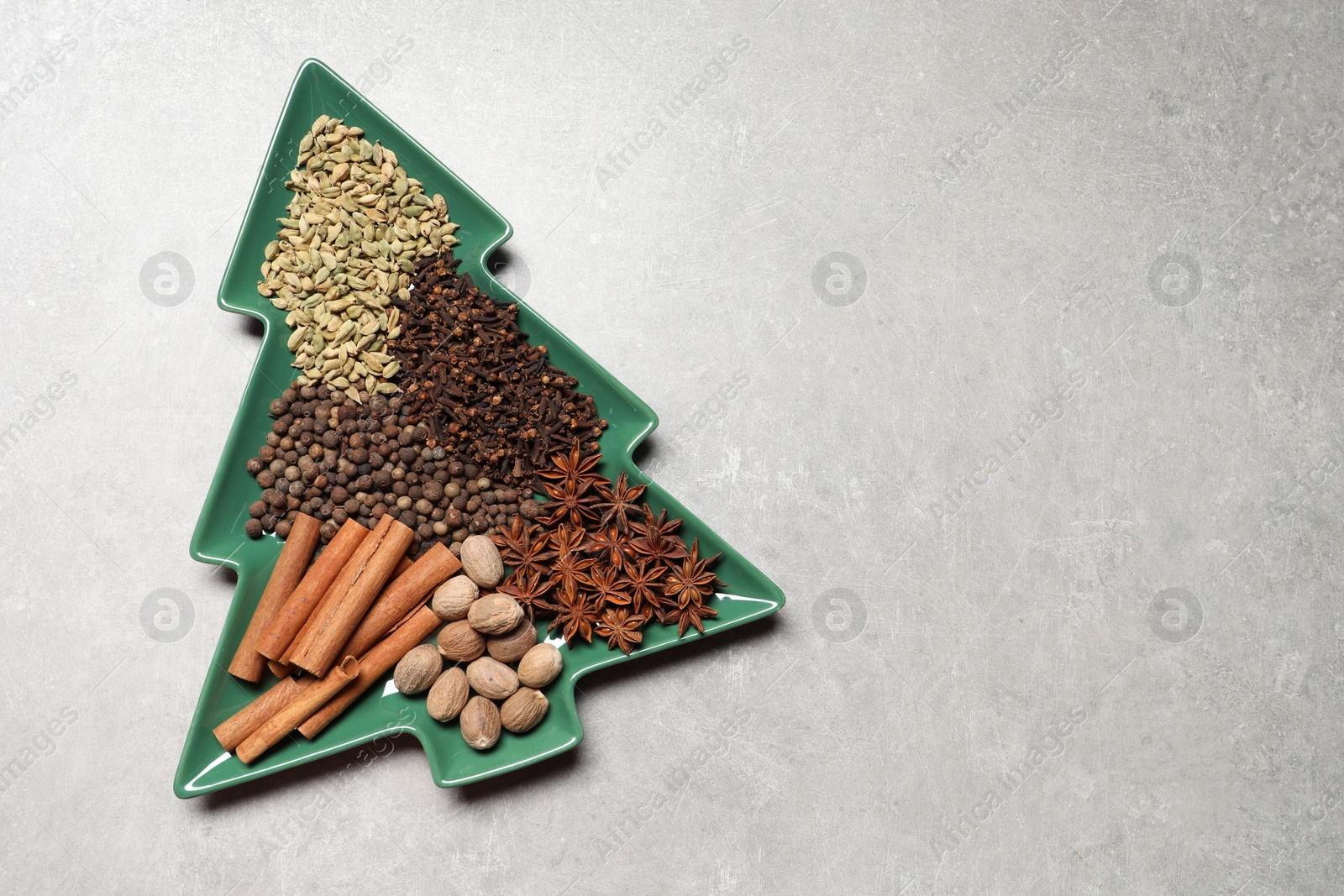 Photo of Different spices and nuts on light gray textured table, top view. Space for text