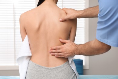 Orthopedist examining woman's back in clinic, closeup. Scoliosis treatment