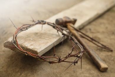 Photo of Crown of thorns, hammer and wooden plank on ground. Easter attributes