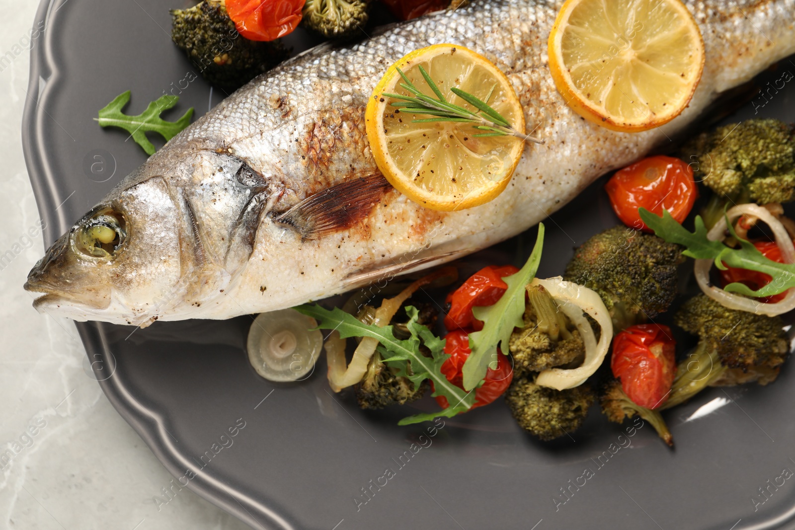 Photo of Baked fish with vegetables, rosemary and lemon on grey textured table, top view