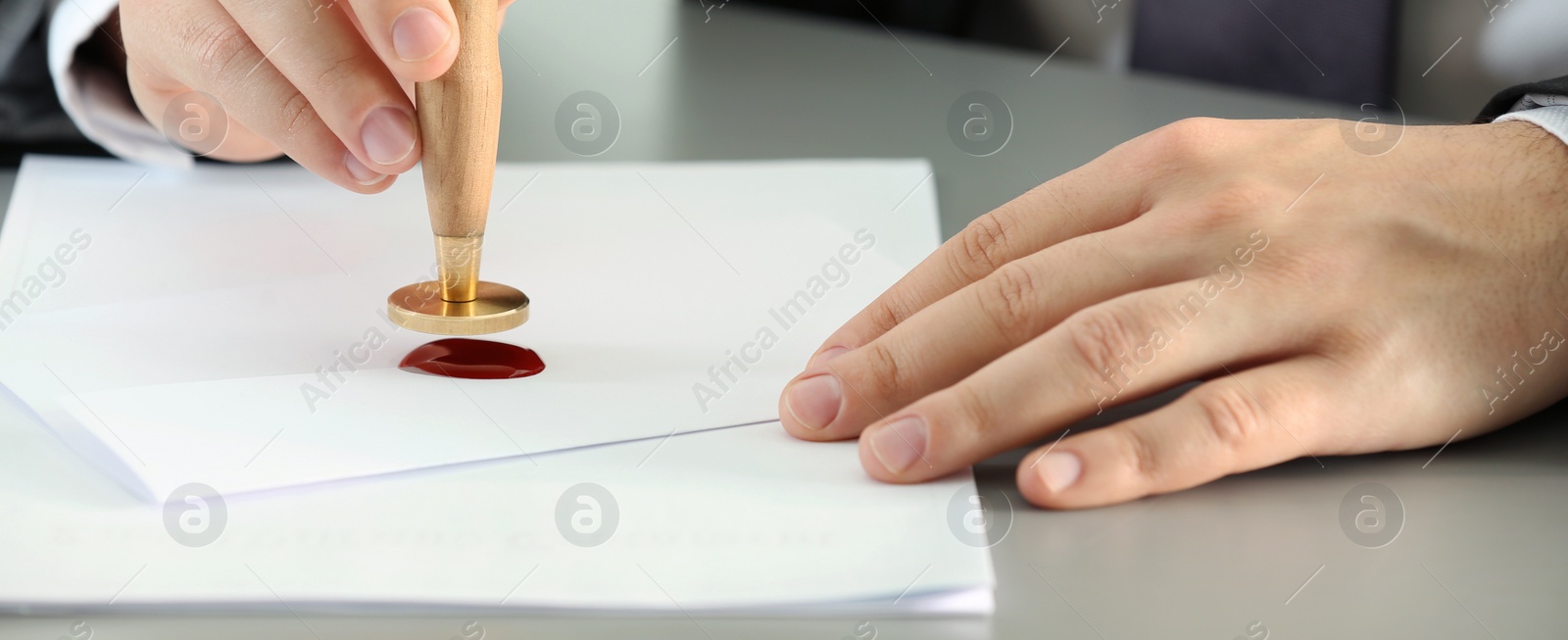 Image of Notary stamping document at table, closeup. Banner design