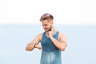 Photo of Young man checking pulse outdoors on sunny day