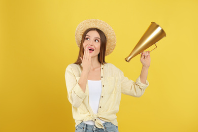 Young woman with megaphone on yellow background