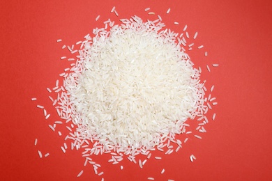 Long grain rice on color background, top view