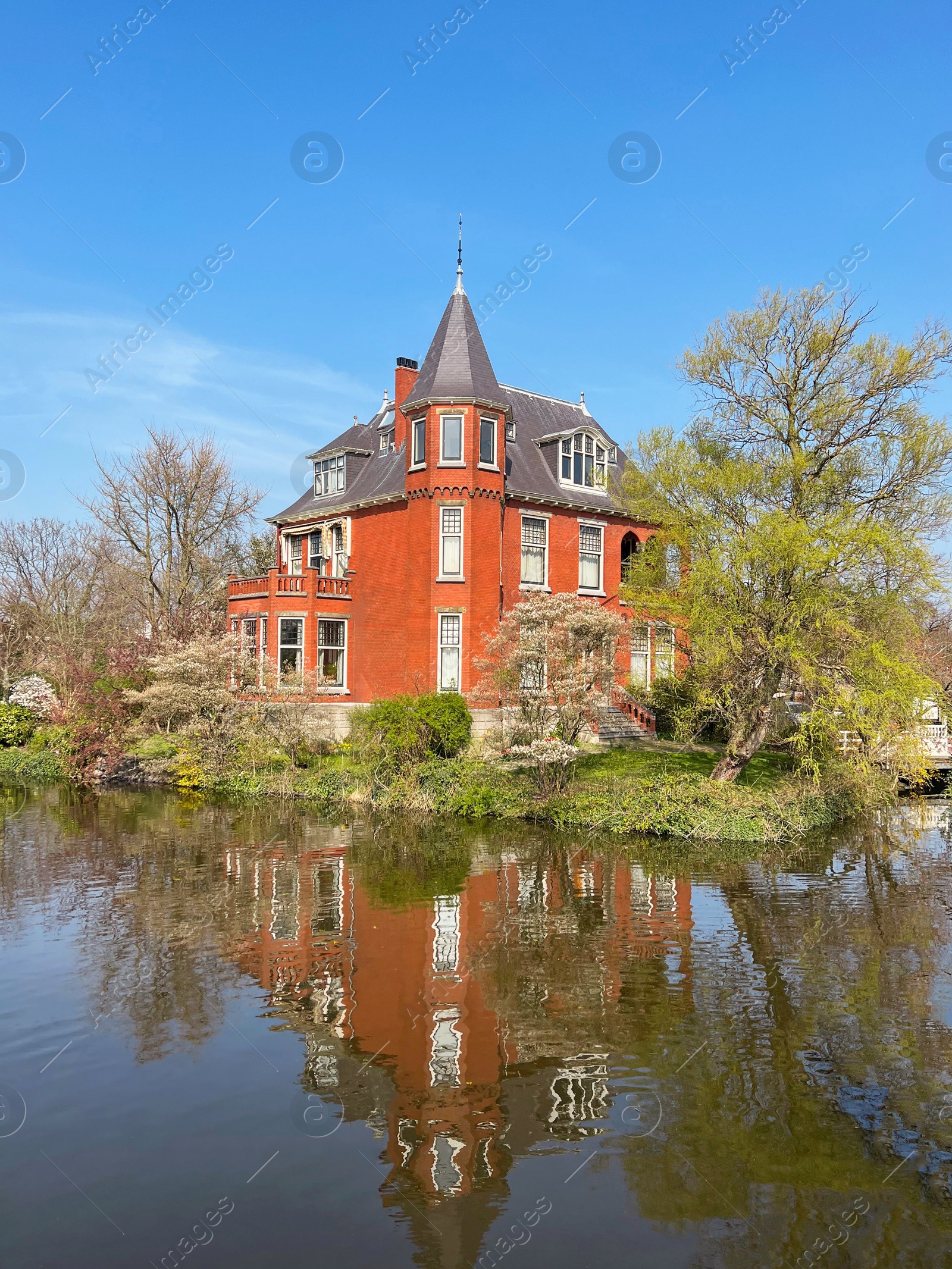 Photo of Picturesque view of beautiful old house near river on sunny spring day