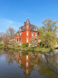 Picturesque view of beautiful old house near river on sunny spring day