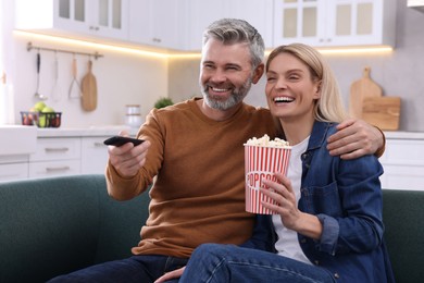 Happy affectionate couple with popcorn spending time together on sofa at home. Romantic date
