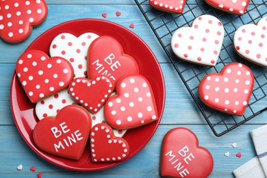 Photo of Decorated heart shaped cookies on blue wooden table, flat lay. Valentine's day treat