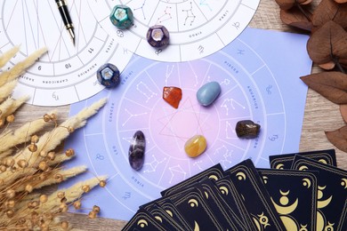 Photo of Zodiac wheels, tarot cards, astrology dices and gemstones on wooden table, flat lay