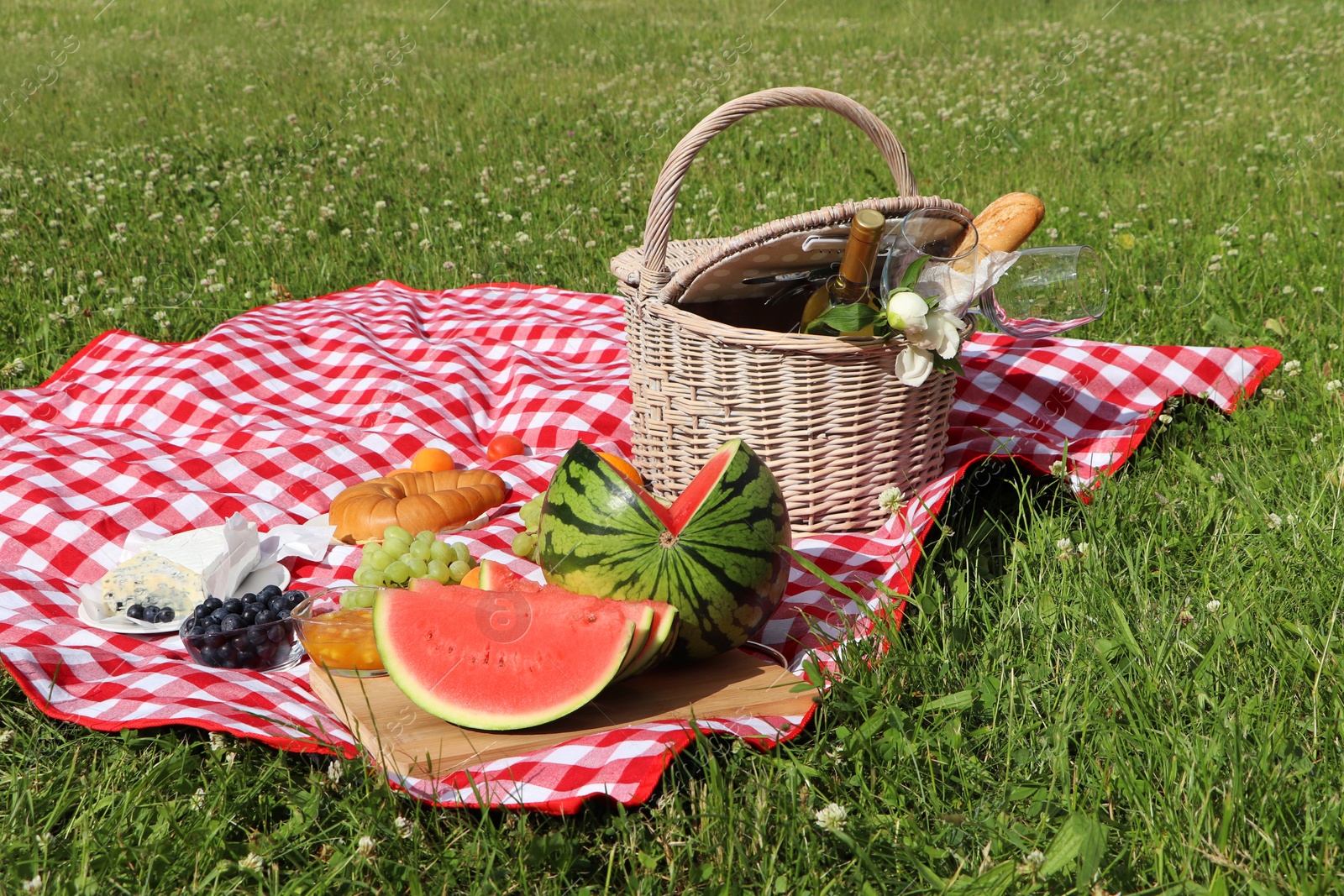 Photo of Picnic blanket with delicious food and wine outdoors on summer day