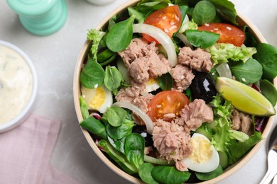 Photo of Bowl of delicious salad with canned tuna and vegetables on light table, top view