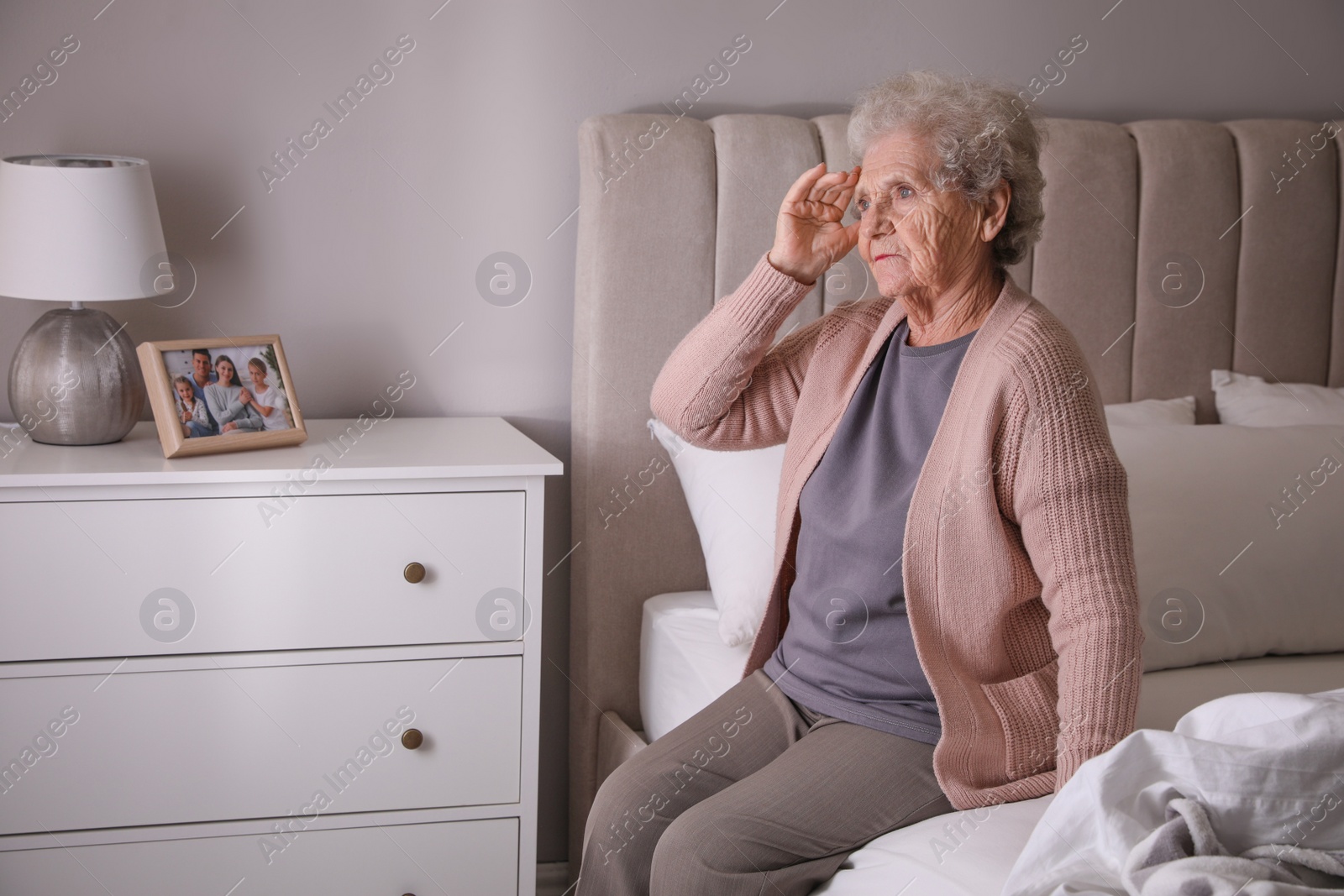 Photo of Senior woman with headache in bedroom at home. Space for text