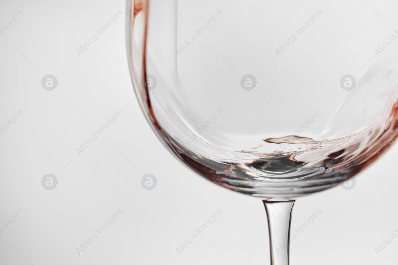 Photo of Pouring rose wine into glass on light background, closeup