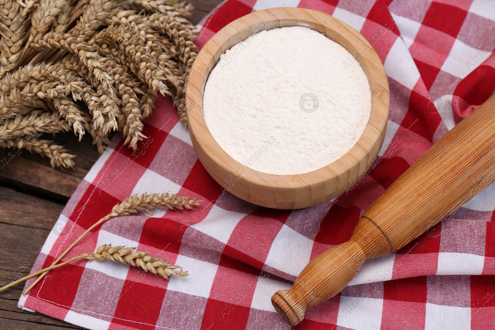 Photo of Ears of wheat and flour on wooden table