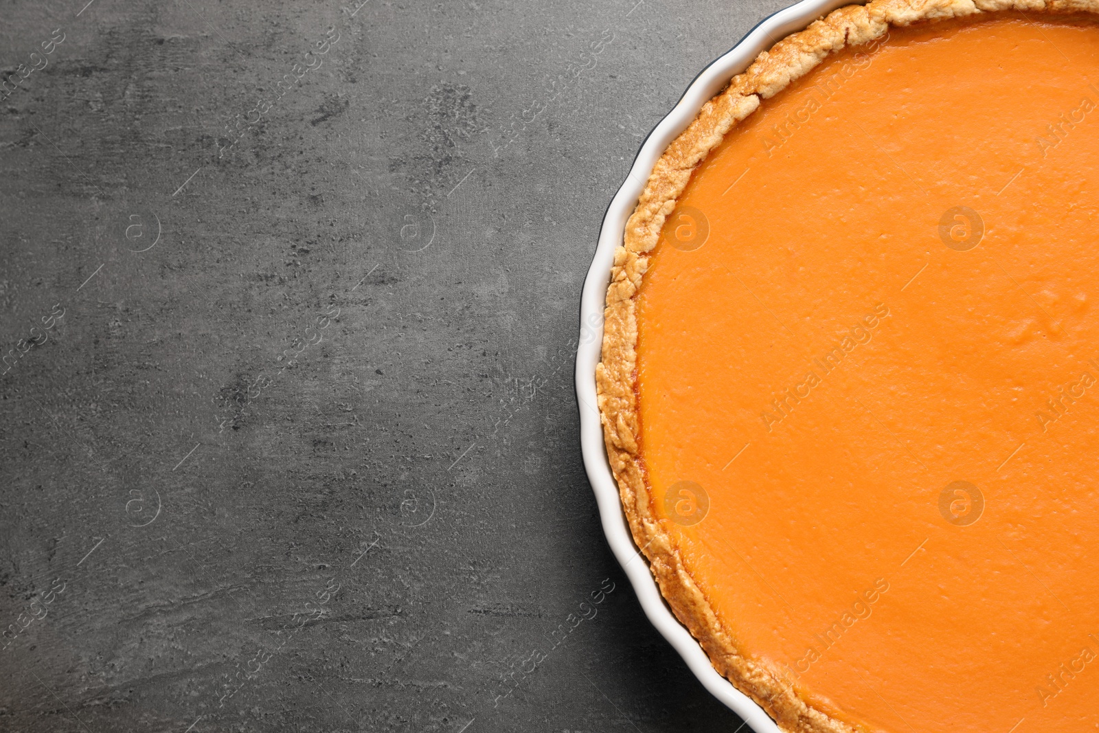 Photo of Fresh delicious homemade pumpkin pie on gray background, top view with space for text