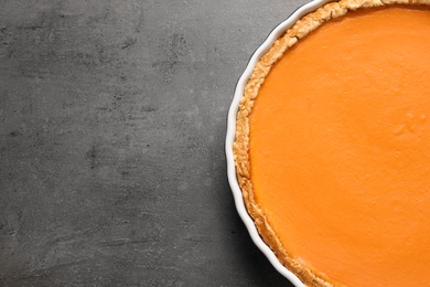 Fresh delicious homemade pumpkin pie on gray background, top view with space for text