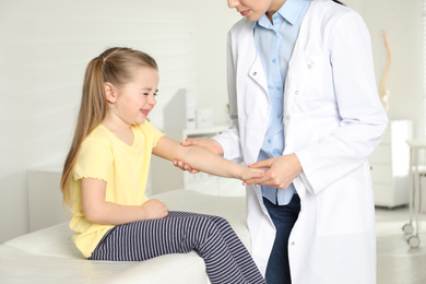 Photo of Professional orthopedist examining little patient's arm in clinic