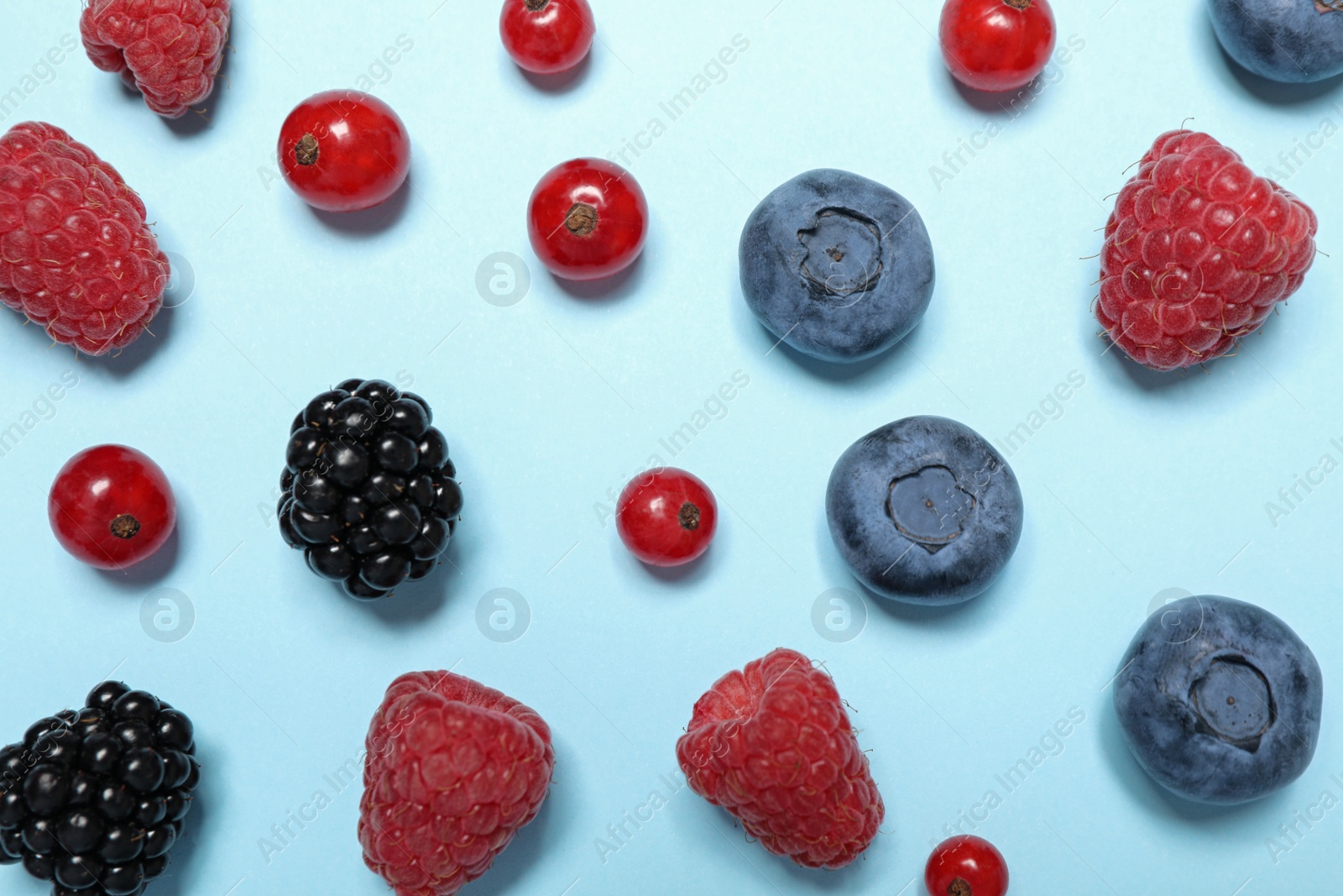 Photo of Different fresh berries on light blue background, flat lay