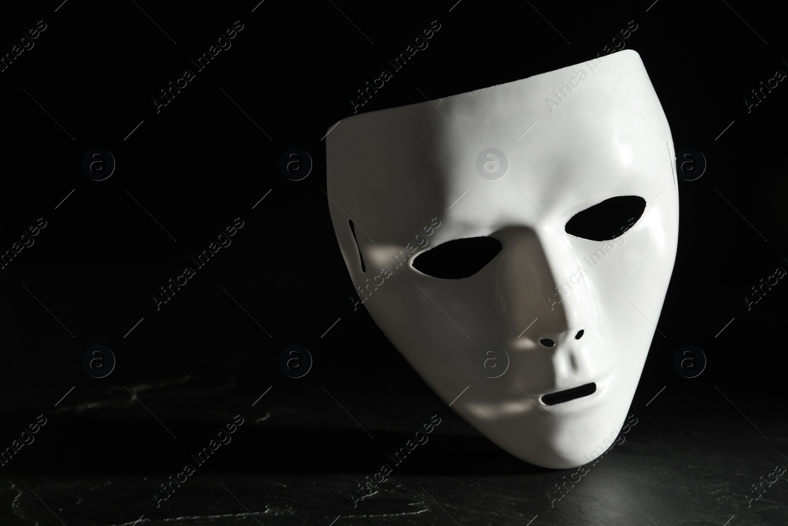 Photo of White theatre mask on black background, space for text