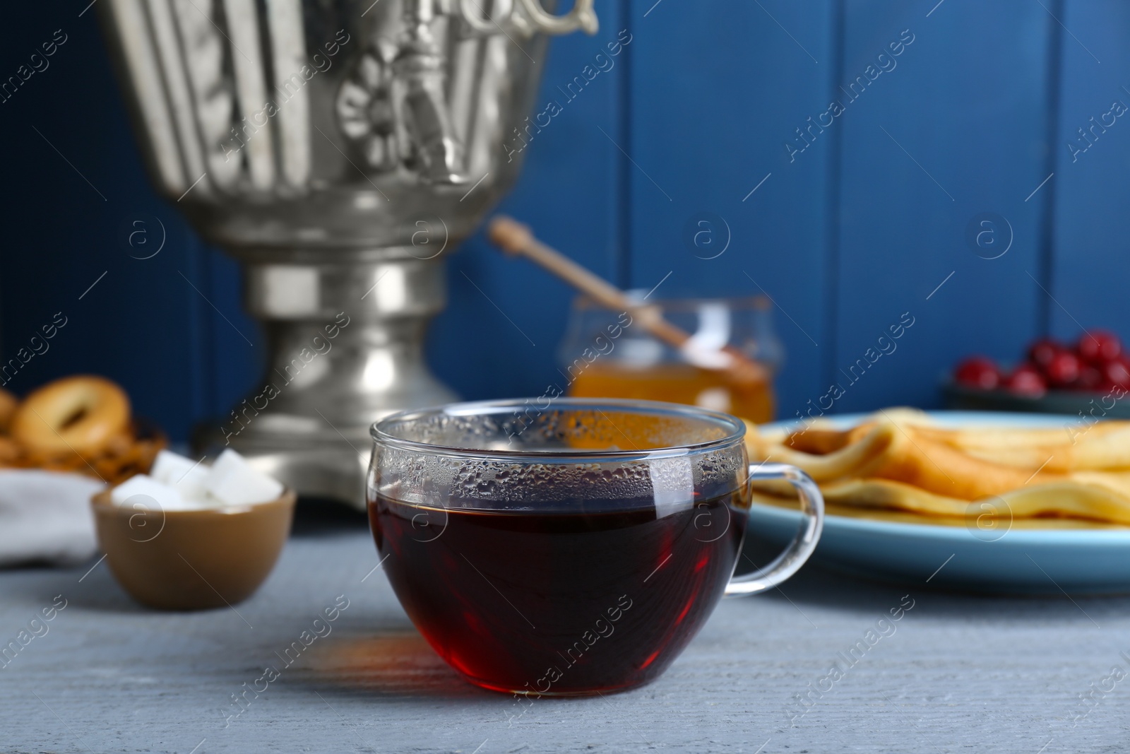 Photo of Glass cup of aromatic tea on light blue wooden table