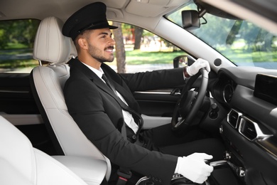 Photo of Young handsome driver in luxury car. Chauffeur service