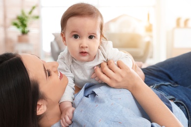 Happy young mother playing with baby on floor at home