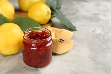 Photo of Delicious quince jam and fruits on light grey table, closeup