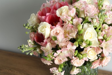 Beautiful bouquet of fresh flowers in vase on wooden table, closeup