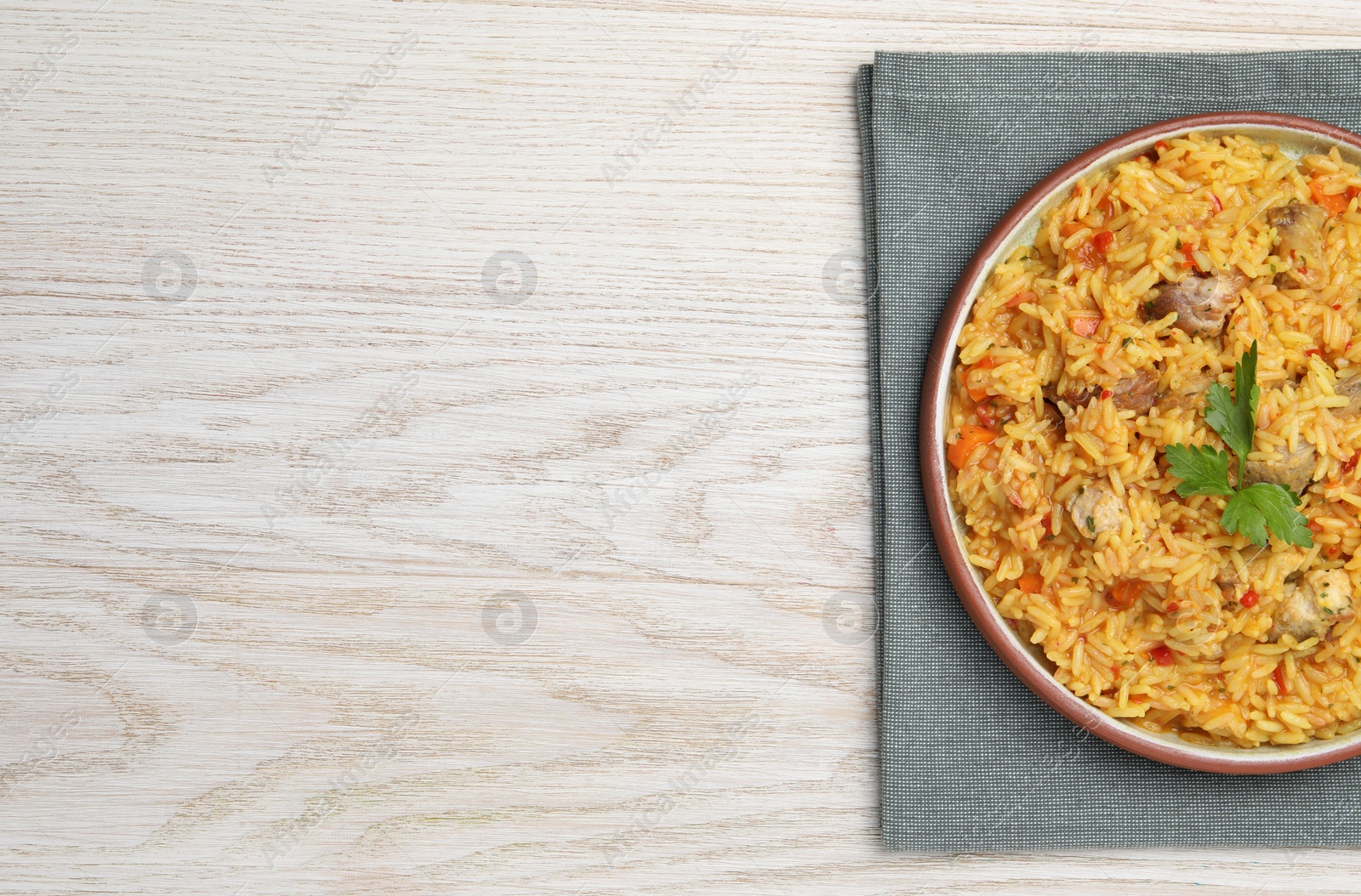 Photo of Delicious pilaf with meat on white wooden table, top view. Space for text