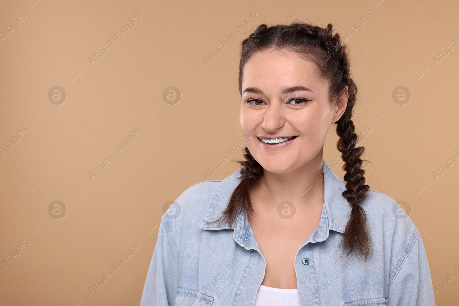 Photo of Smiling woman with braces on beige background. Space for text