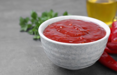 Photo of Bowl of hot chili sauce and ingredients on table, closeup. Space for text