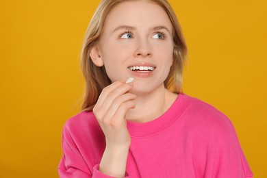 Photo of Happy young woman with bubble gum on yellow background