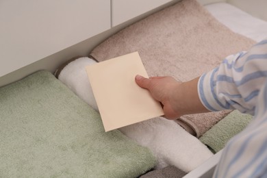 Photo of Woman putting scented sachet into drawer with towels, closeup