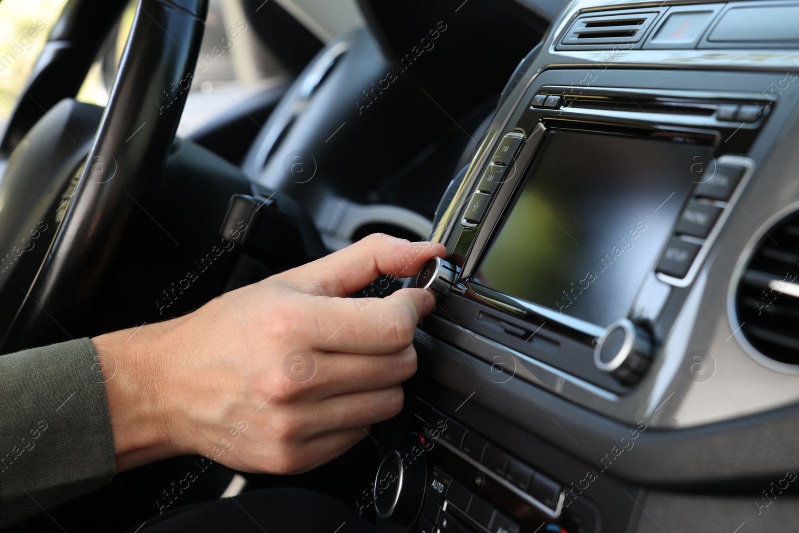 Photo of Listening to radio while driving. Man turning volume button on vehicle audio in car, closeup