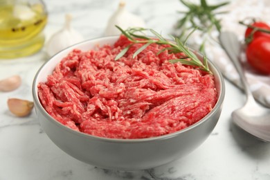 Photo of Fresh minced meat in ceramic on white marble table, closeup