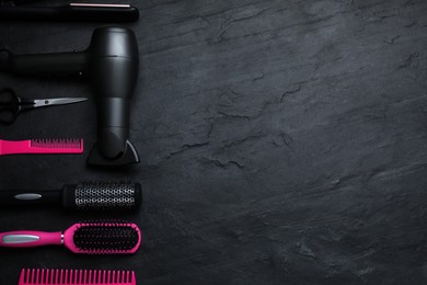 Flat lay composition of professional hairdresser tools on dark grey table, space for text