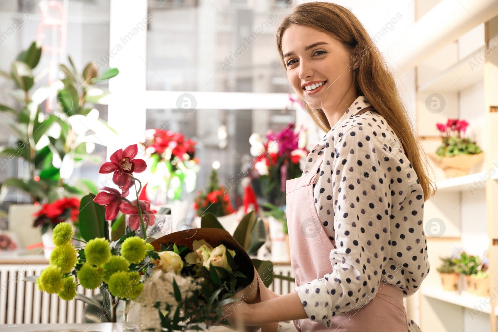 Photo of Professional florist with bouquet of fresh flowers in shop