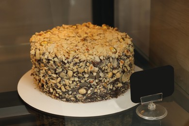 Photo of Delicious cake with nuts on counter in store, closeup