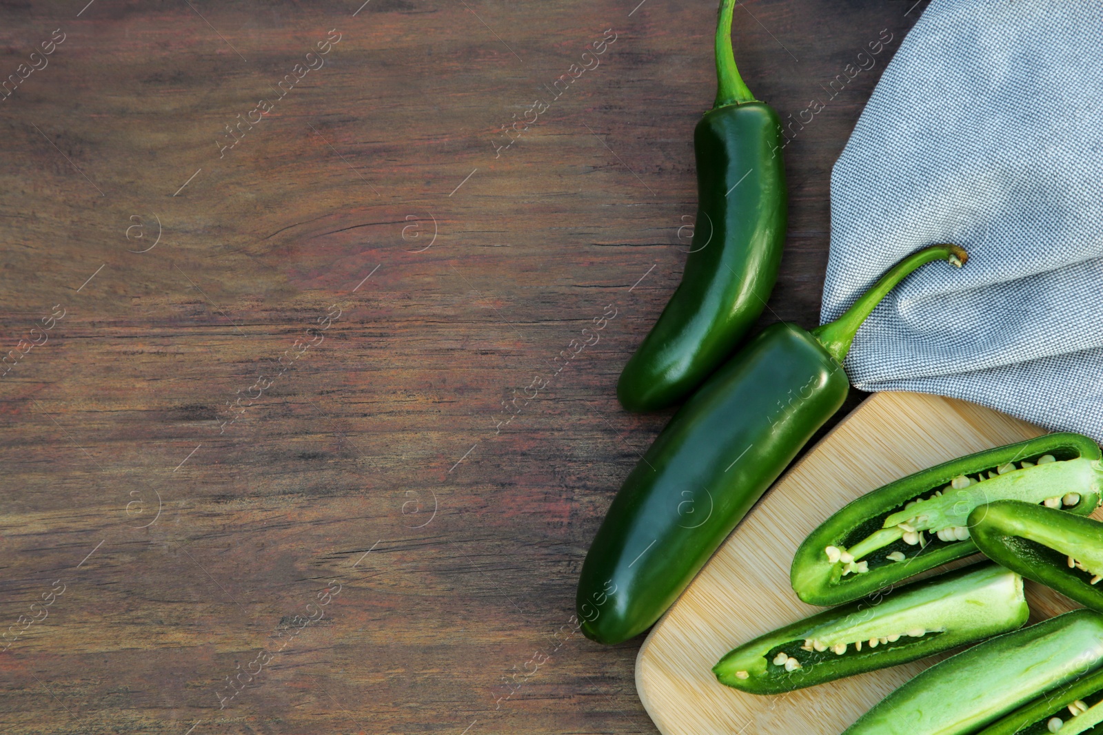 Photo of Fresh green jalapeno peppers on wooden table, flat lay. Space for text