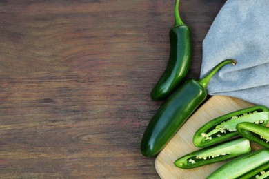 Photo of Fresh green jalapeno peppers on wooden table, flat lay. Space for text